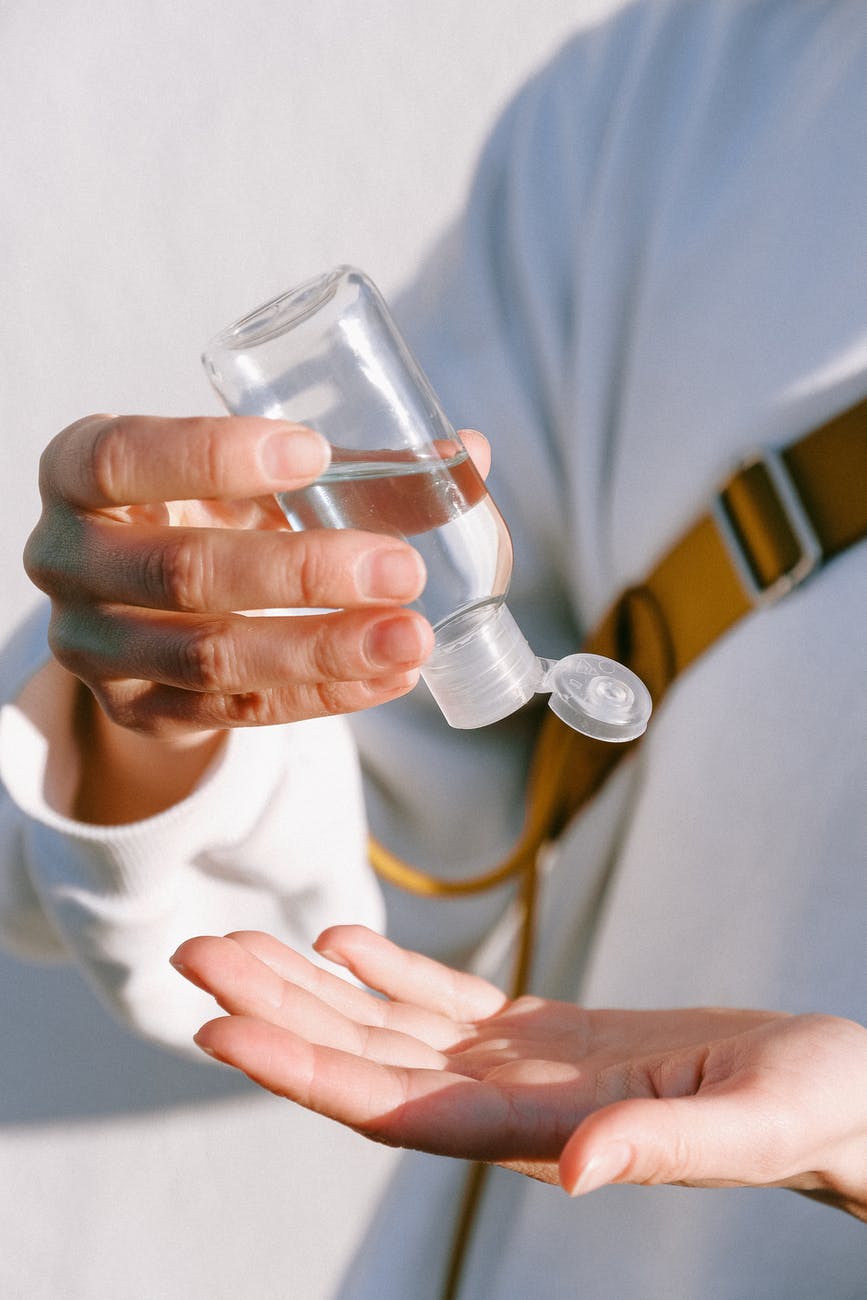 person in white long sleeve shirt holding clear bottle